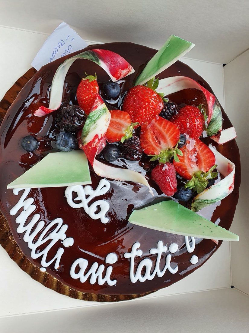 A glossy chocolate-glazed celebration cake topped with fresh strawberries, blueberries and blackberries